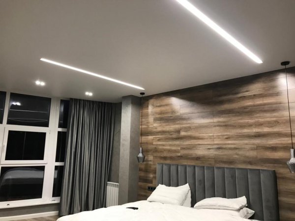 Пример натяжного потолка со световыми линиями в спальню